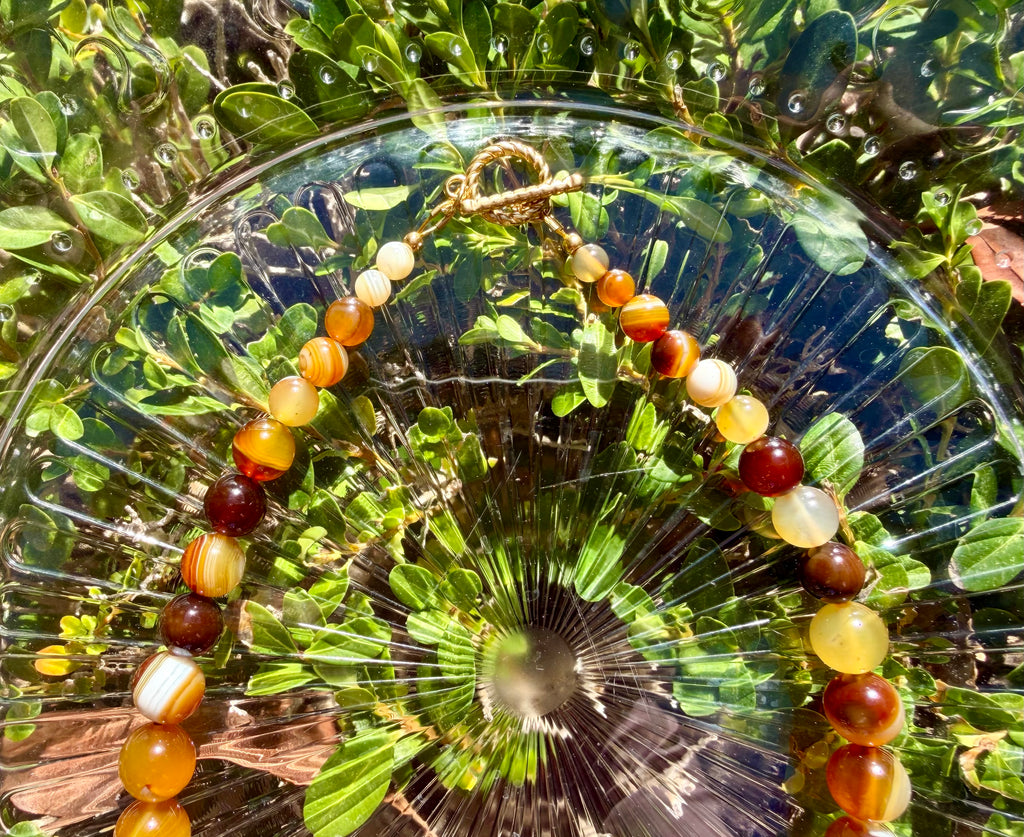 Close-up view of the decorative gold toggle clasp and smaller banded agate beads at the back of the gradient stone necklace.